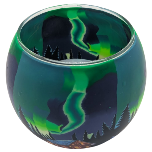 Glass light globe with a design of the Northern Lights over a cabin in the woods.